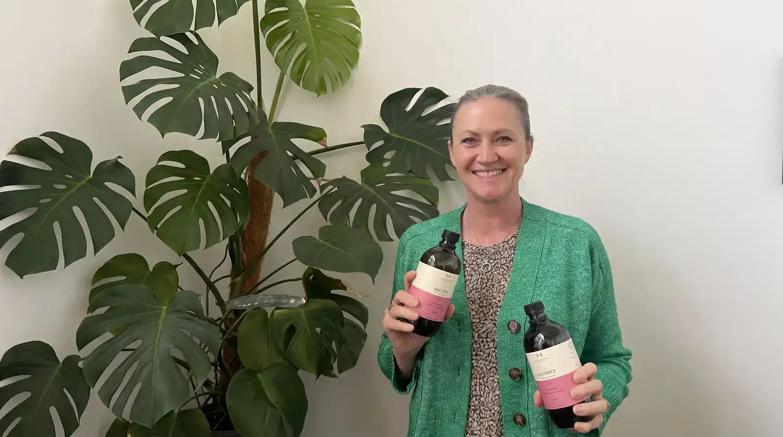 A naturopath holding two liquid herbal extracts from the clinic dispensary