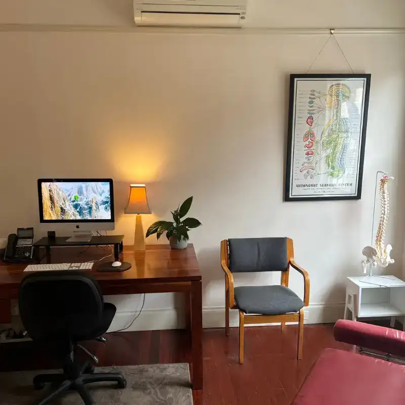 A naturopathic consultation room, set up with a desk and two chairs