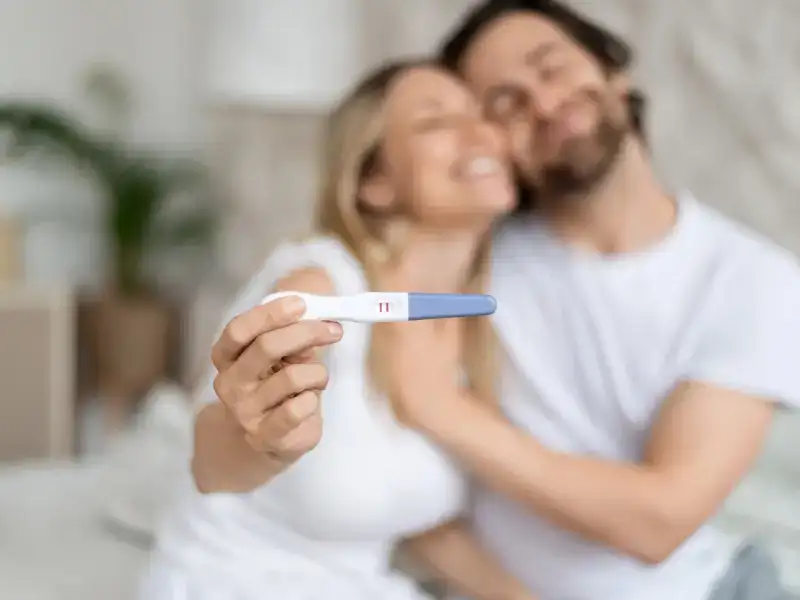 A couple embracing while holding up a positive pregnancy test