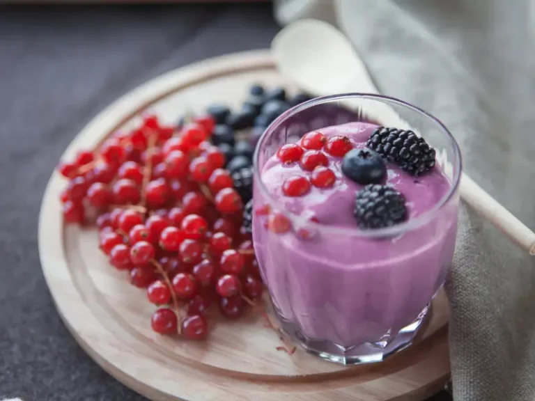 Antioxidant-rich berry smoothie with redcurrants, blueberries and blackberries on a wooden board